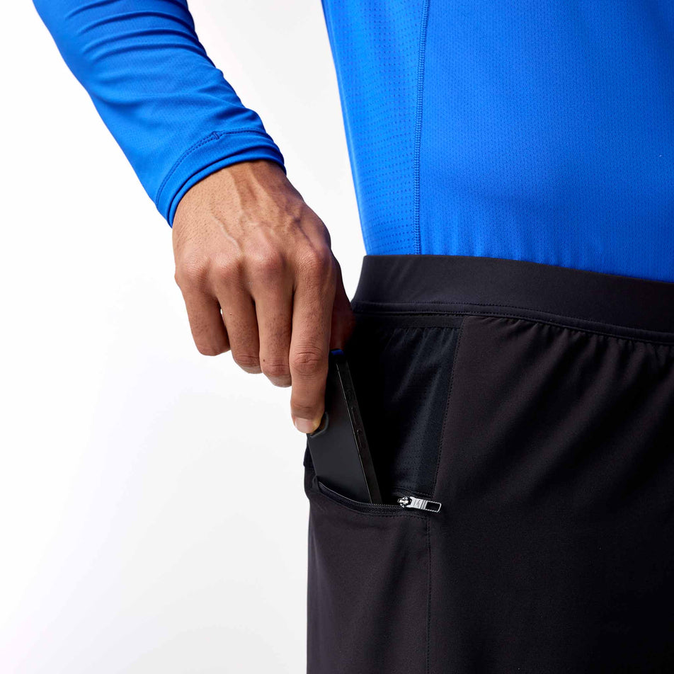 A model demonstrating the side zip pocket on the Brooks Men's Journey 7