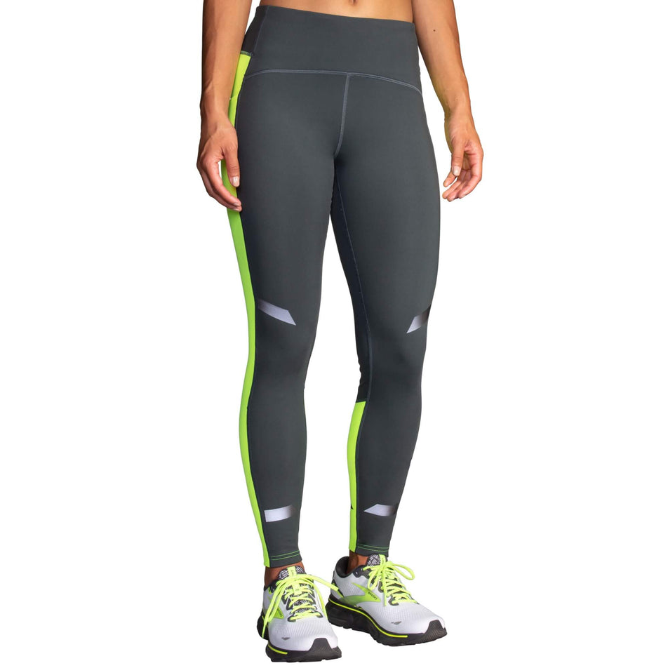 Front view of a model wearing a pair of Brooks Women's Run Visible Thermal Tights in the Asphalt/Nightlife colourway. Model is also wearing a pair of Brooks running shoes.  (8065569194146)