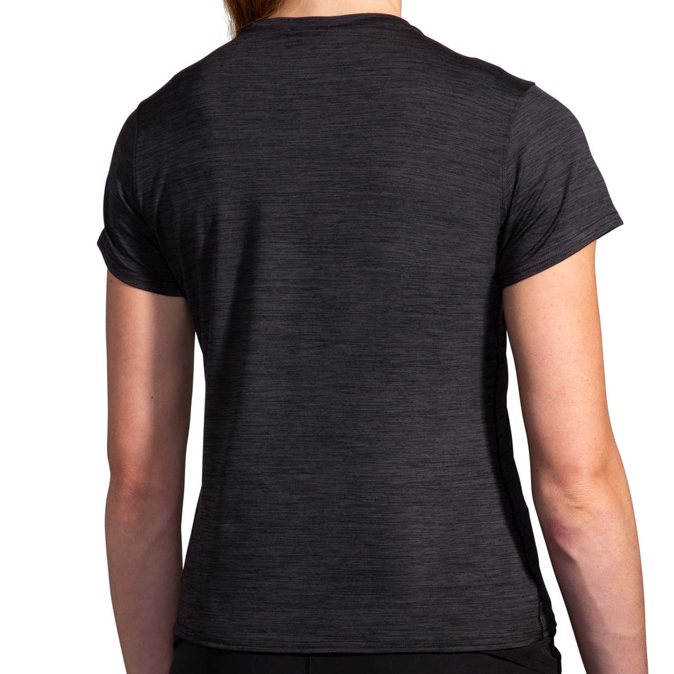 Back view of a model wearing the Women's Luxe Short Sleeve in the Heather Deep Black colourway. Model is also wearing Brooks legwear. (8177471488162)