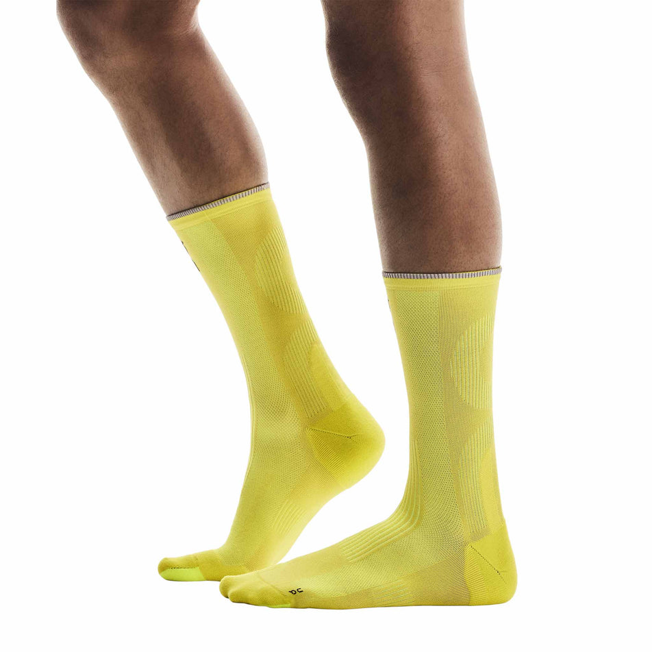 Side view of a model wearing a pair of On Unisex Elite Run Sock High in the Lime colourway. (8717355712674)