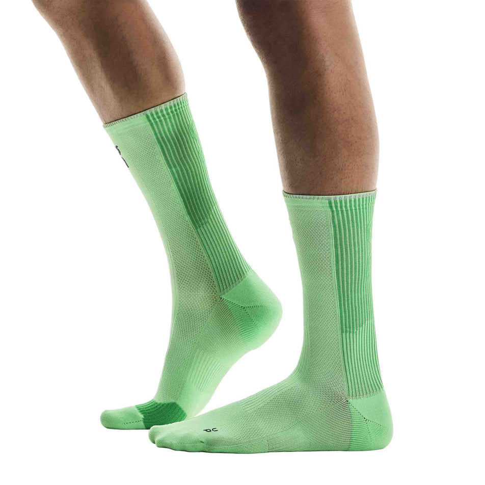 Side view of a model wearing the On Unisex Performance Run Sock High in the Honeydew/Parsley colourway. (8717316260002)