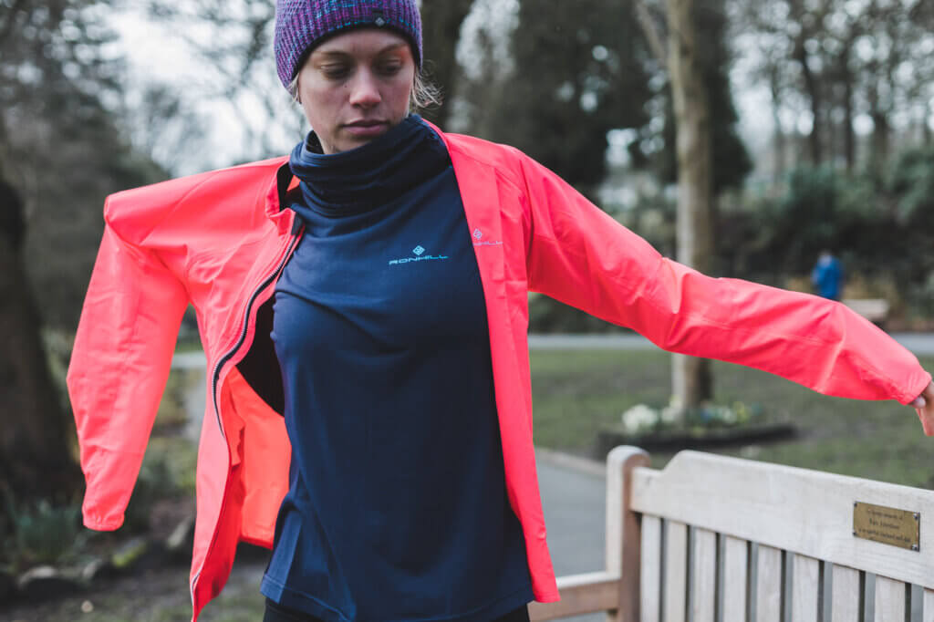 Model putting on a Ronhill women's Core Jacket