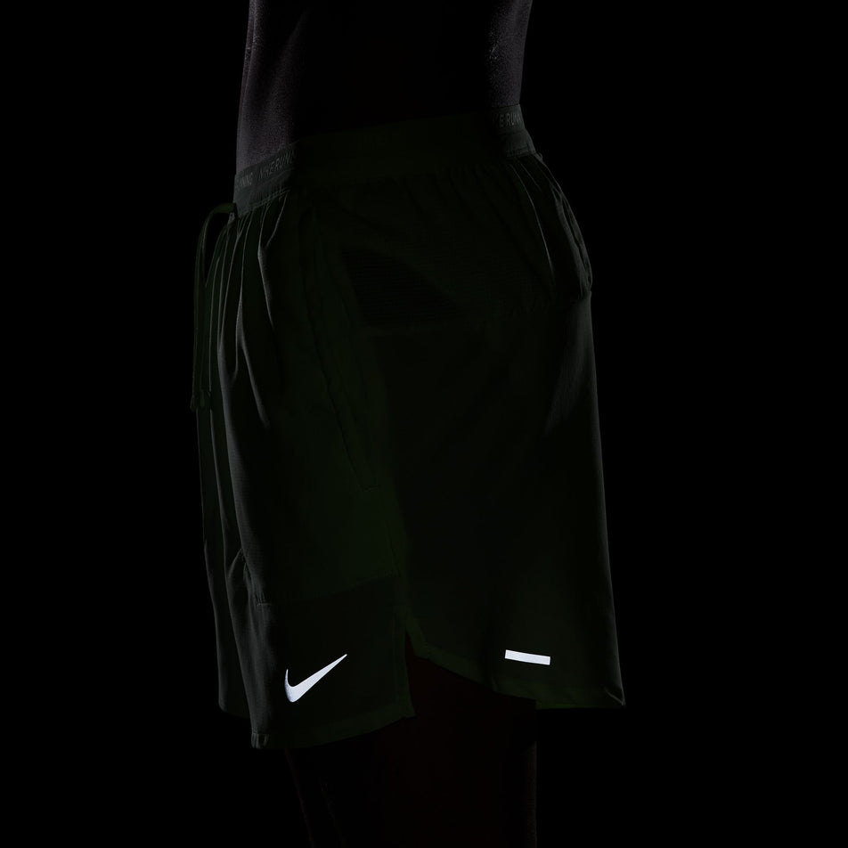 The reflective Nike SWOOSH on the front and reflective tape on the back of a pair of Nike Men's Stride Dri-FIT 5