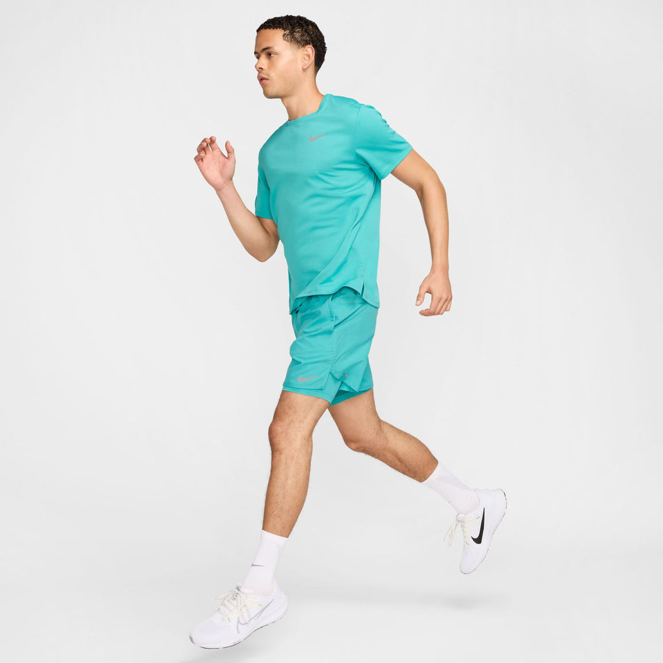 Angled view of a model wearing the Nike Men's Miler Dri-FIT UV Short-Sleeve Running Top in the Dusty Cactus/Reflective Silver colourway. (8562855116962)