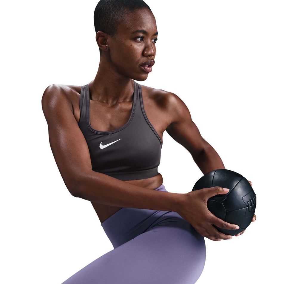 Angled view of a model wearing the Nike Women's Swoosh High Support Non-Padded Adjustable Bra in the Thunder Grey colourway. (8692875165858)
