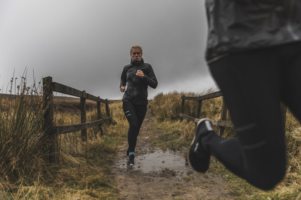 Women running along a trail in bad weather