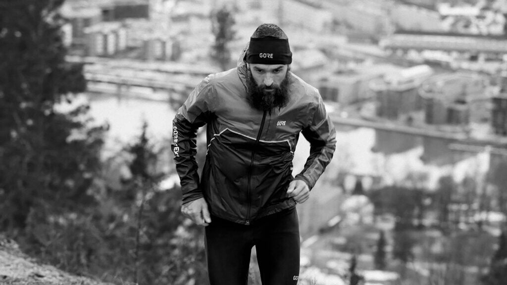 Man running up a hill in a GORE® Wear Jacket