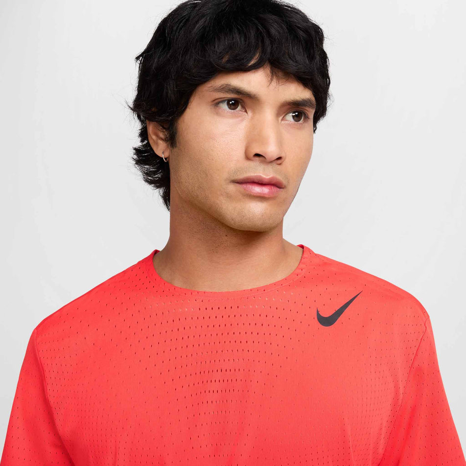 Close up view of the chest area on the Nike Men's AeroSwift Dri-FIT ADV Short-Sleeve Running Top in the Light Crimson/Black colourway. (8560409706658)