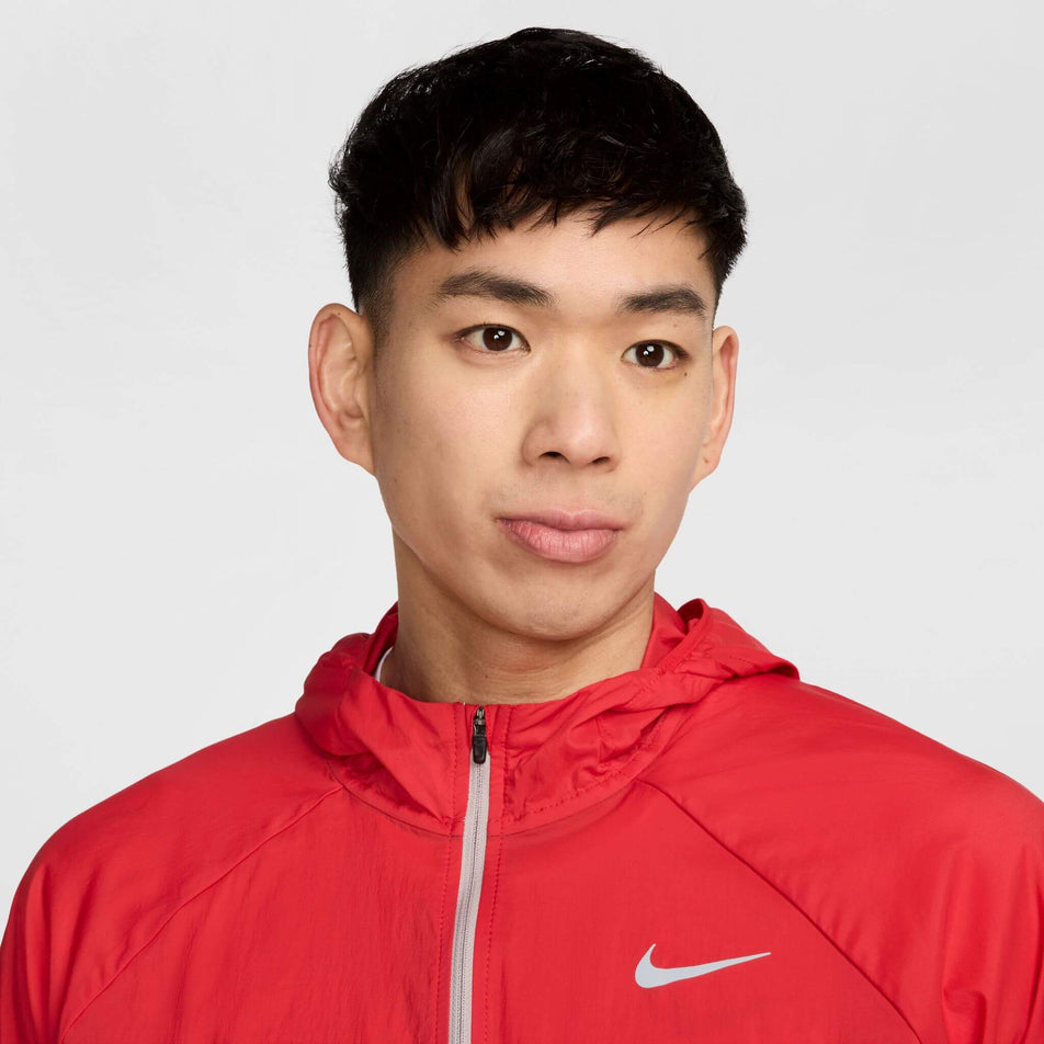Close-up front view of a model wearing a Nike Men's Stride Repel UV Running Jacket in the University Red/Reflective Silver colourway. (8591132655778)