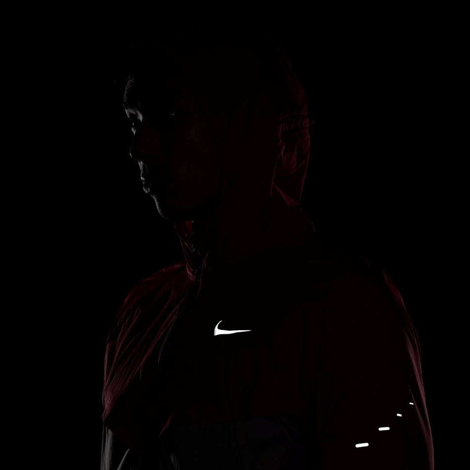 The front reflectivity and left-side reflectivity on a Nike Men's Stride Repel UV Running Jacket in the University Red/Reflective Silver colourway. Jacket is being worn by a model. (8591132655778)