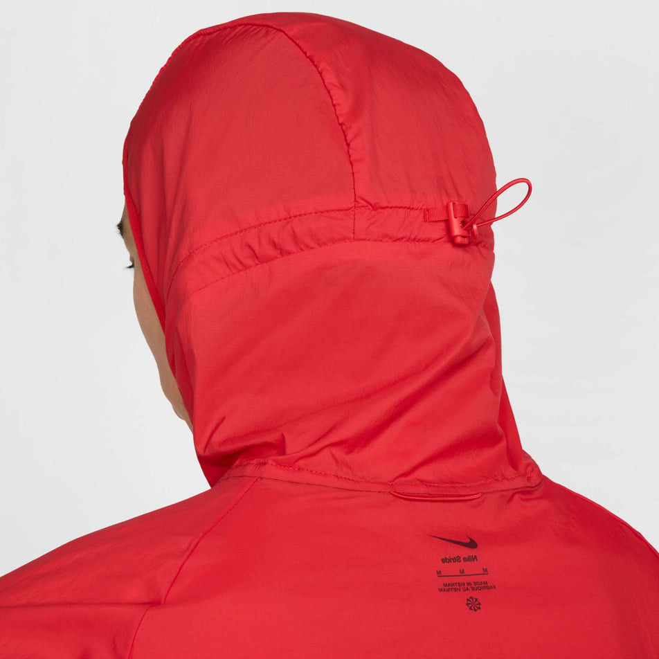 Close-up of a model wearing a Nike Men's Stride Repel UV Running Jacket, in the University Red/Reflective Silver colourway, with the hood up. (8591132655778)