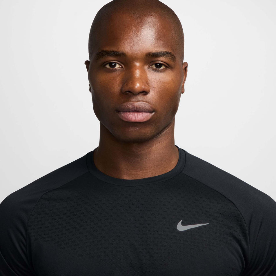 Close up view of the chest area of the Nike Men's Stride Dri-FIT ADV Short-Sleeve Running Top in the Black/Reflective Silver colourway.(8560160735394)