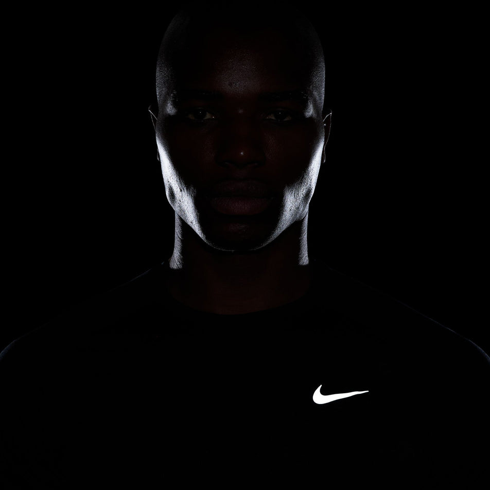 The reflective Swoosh and reflective strips on the front of the Nike Men's Stride Dri-FIT ADV Short-Sleeve Running Top in the Black/Reflective Silver colourway. (8560160735394)