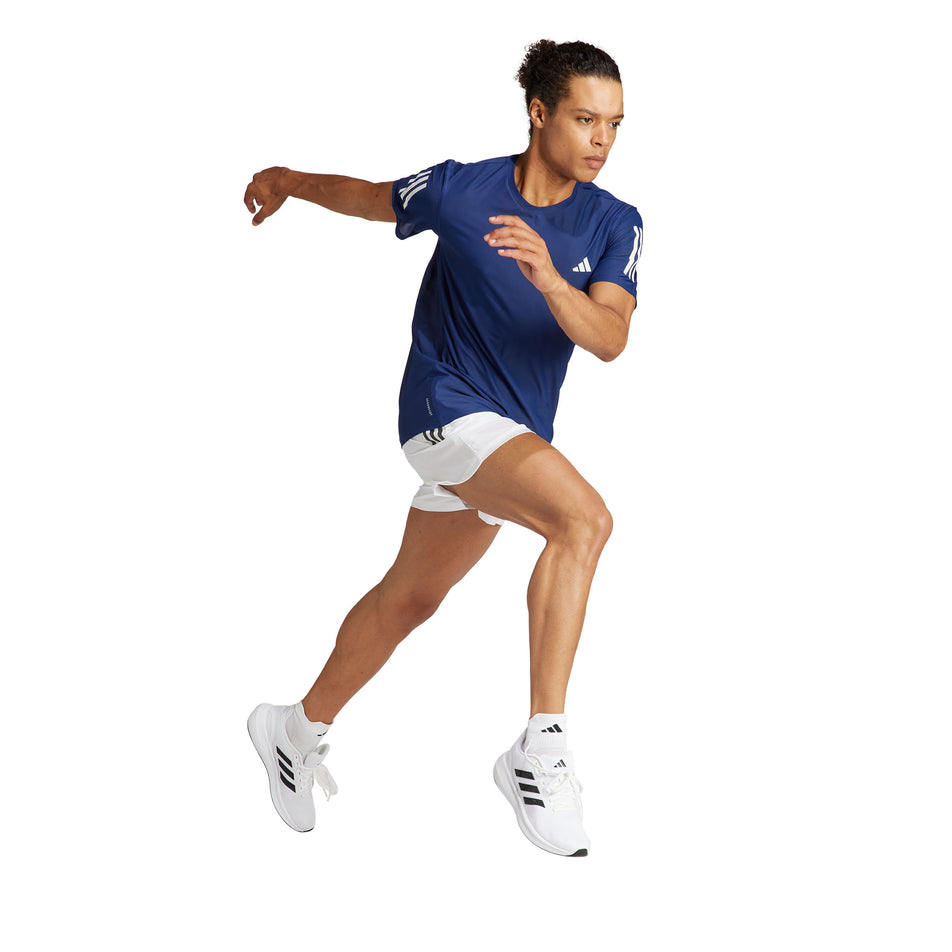 A model wearing an adidas Men's Own The Run T-Shirt in the Dark Blue colourway. Model is also wearing adidas legwear, socks and shorts, and is in a running pose. (8449482588322)