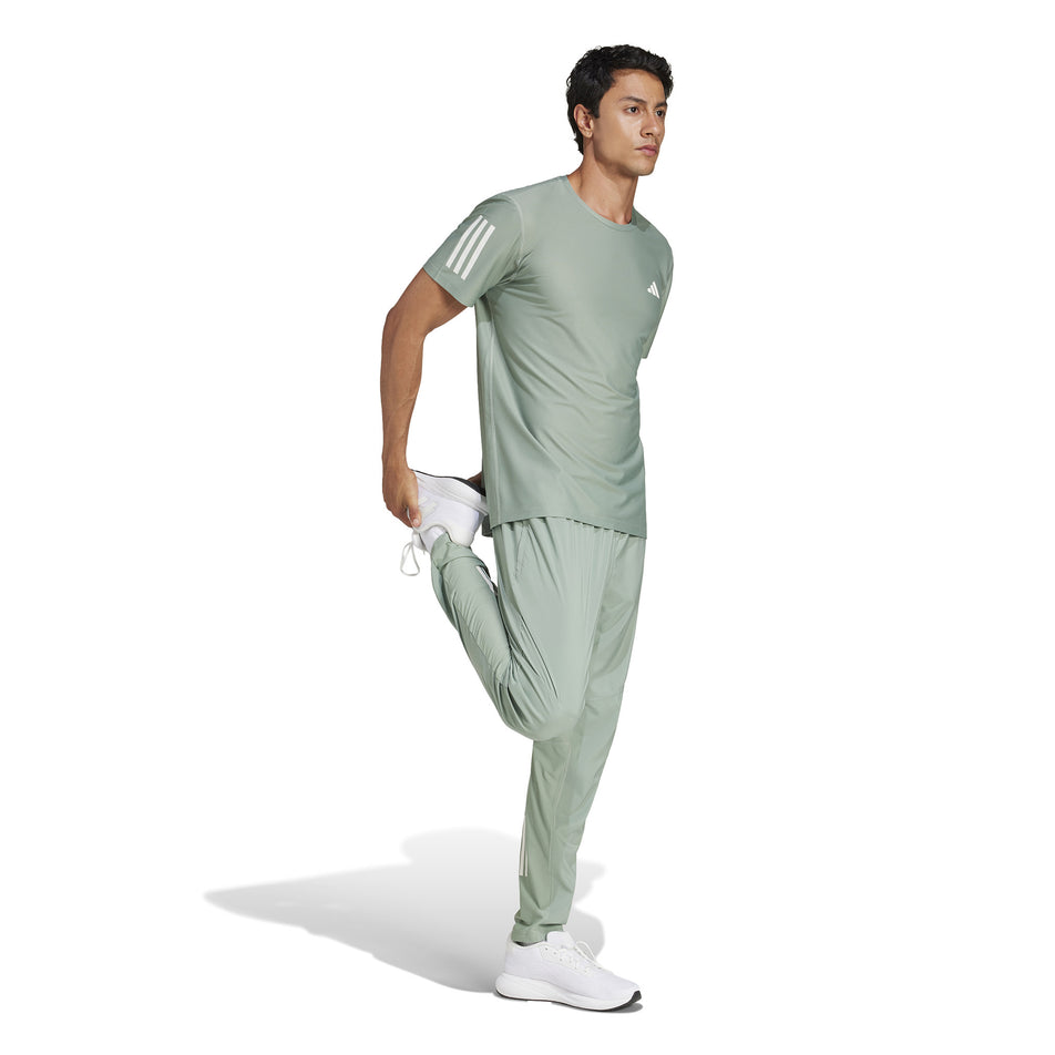Front view of a model wearing the adidas Men's Own The Run Base Tee in the Silver Green colourway. (8566974873762)