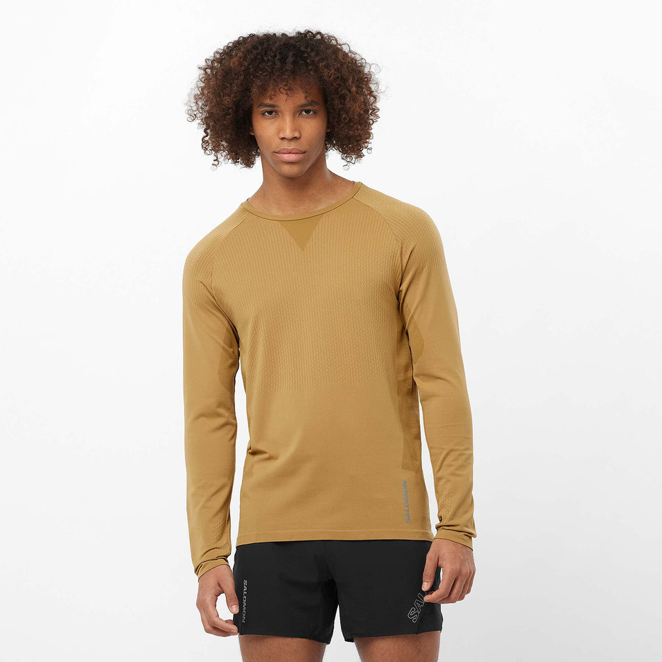 Front view of a model wearing the Salomon Men's Aero Seamless Long-Sleeve T-Shirt in the Antique Bronze colourway. Model is also wearing shorts. (8509564846242)