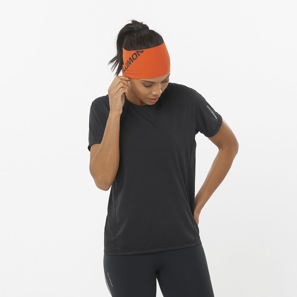 Front view of a model wearing a Salomon Women's Sense Aero Short Sleeve T-Shirt in the Deep Black colourway. Model is also wearing leggings and a headband. (8462977695906)