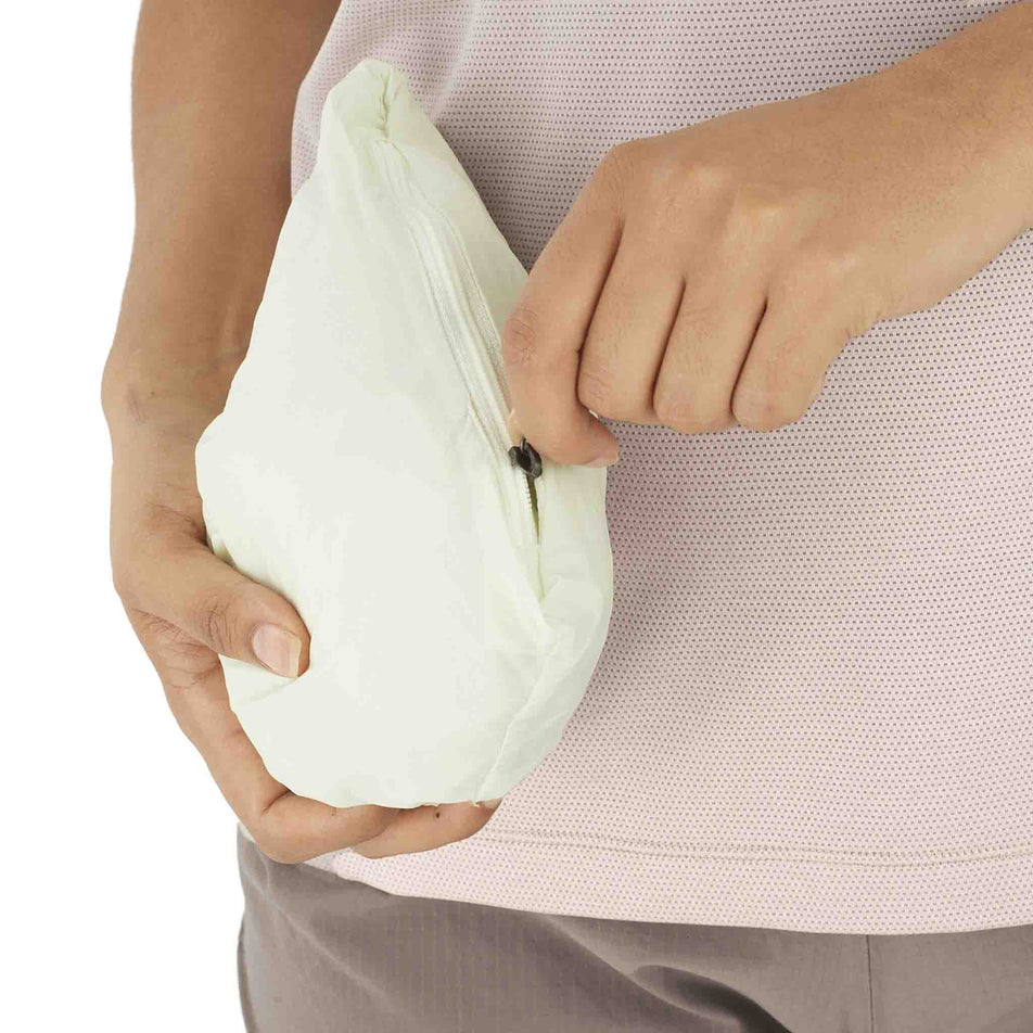 The Salomon Women's SHKout FLY Wind Jacket in the Icicle colourway stowed into the pocket. (8574551556258)