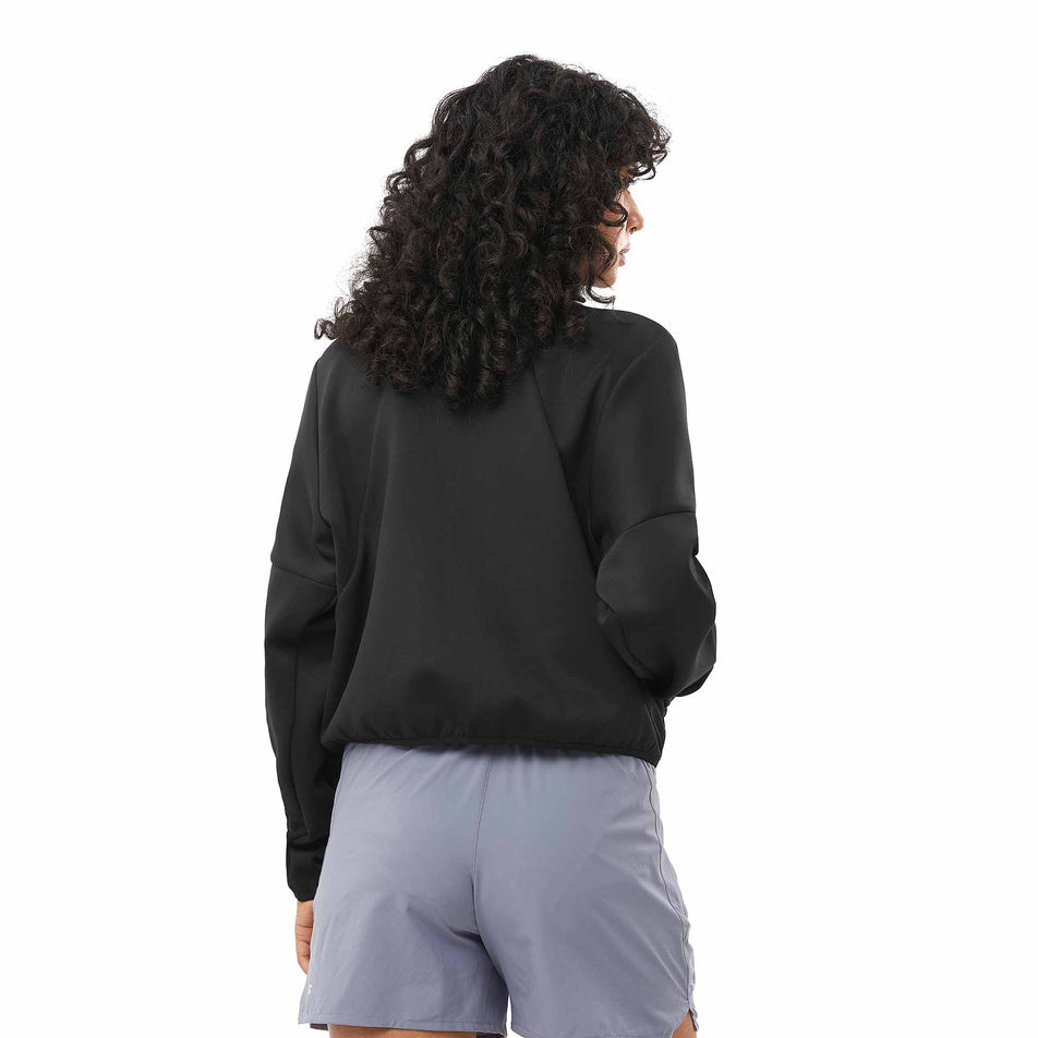 Back view of a model wearing the Salomon Women's SHKout Half Zip Midlayer in the Deep Black colourway. (8575544721570)