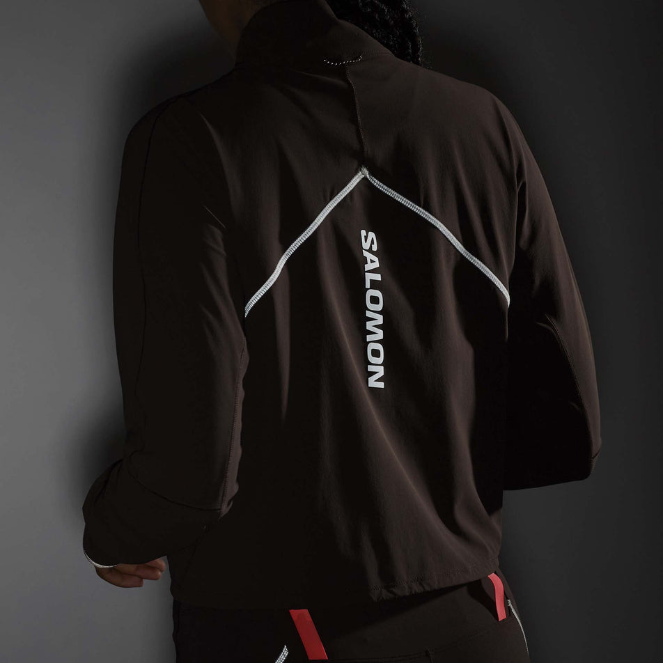 The reflective Salomon graphic and stitching on the back of the Salomon Women's Sense Aero Hybrid Cropped Half Zip Midlayer in the Coffee Bean colourway. (8577396867234)