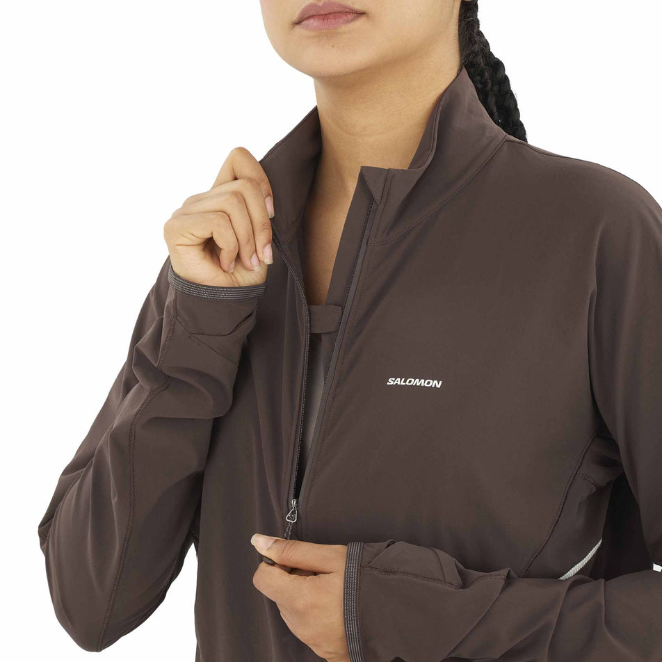 A model demonstrating the zip on the front of the Salomon Women's Sense Aero Hybrid Cropped Half Zip Midlayer in the Coffee Bean colourway. (8577396867234)