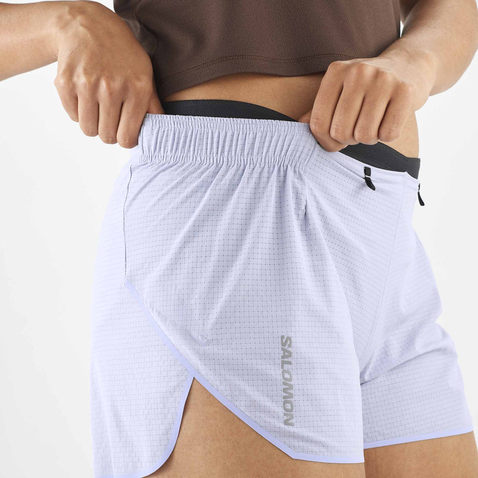 A model demonstrating one of the drop in pockets on the side of the Women's Salomon Sense Aero 3