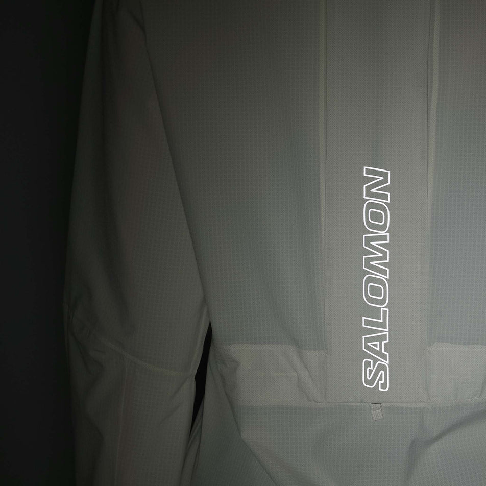 The reflective Salomon logo on the back of the Salomon Women's Bonatti Trail Shell Jacket in the Icicle colourway. (8576408846498)