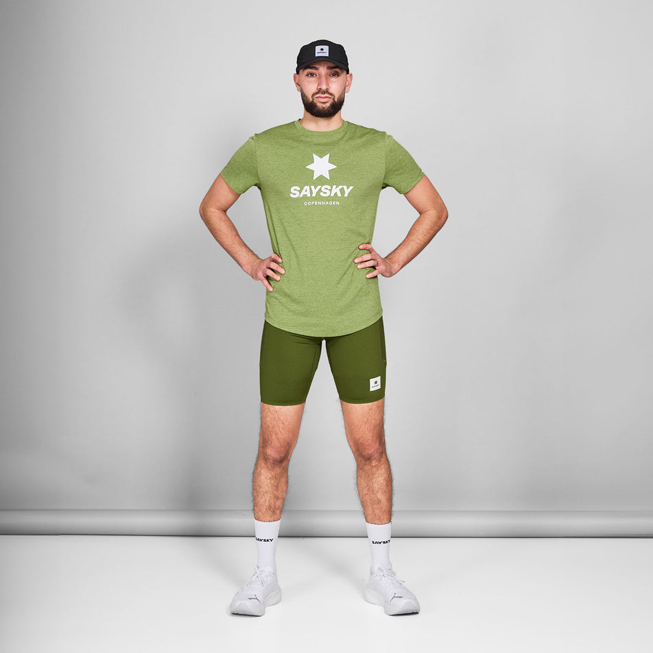 Front view of a model wearing a SAYSKY Men's Logo Combat Pro T-Shirt in the Green Melange colourway. Model is also wearing shorts, socks, shoes, and a cap. (8644805755042)