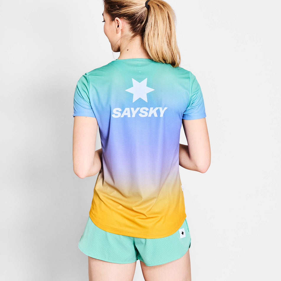 Back view of a model wearing the SAYSKY Women's Drip Dye Flow T-Shirt in the Purple AOP colourway. Model is also wearing shorts. (8675475030178)