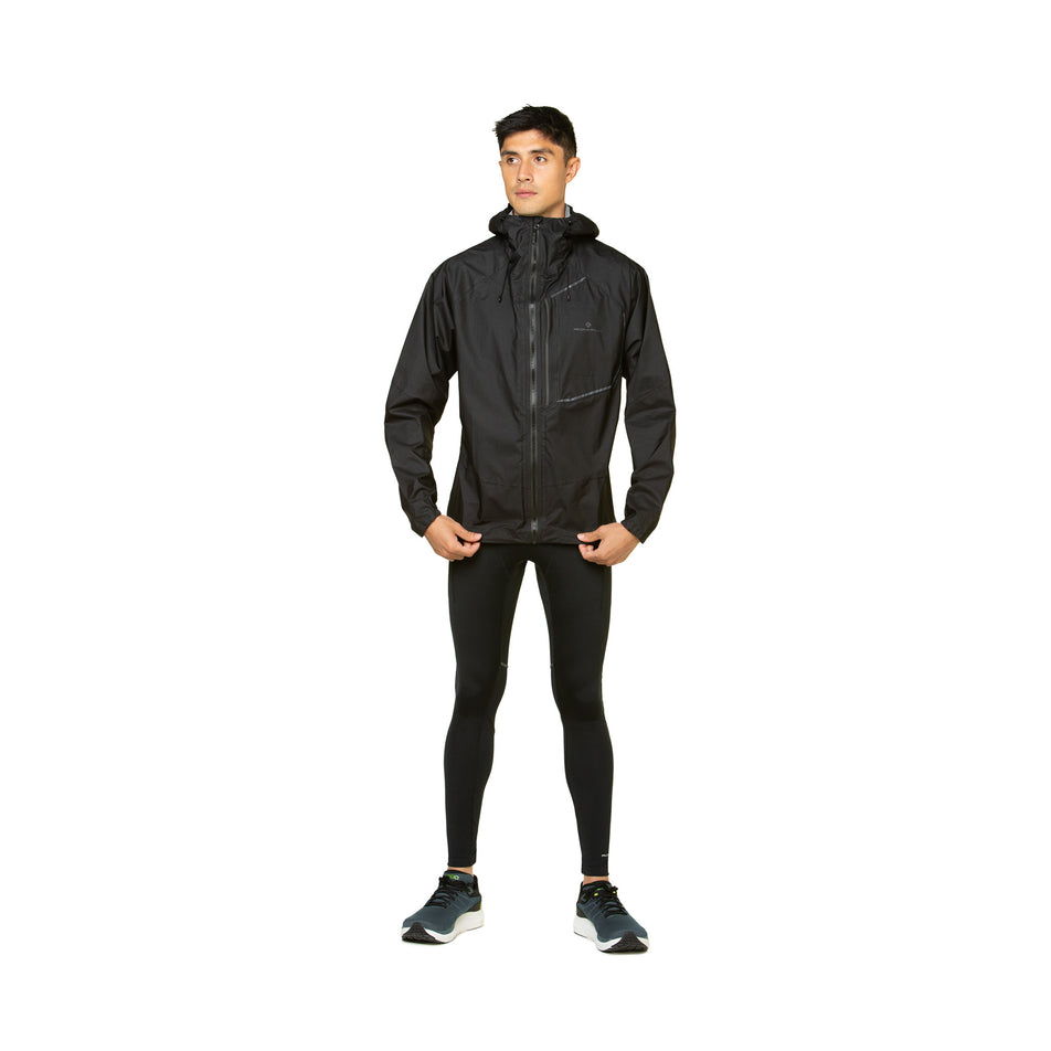 Front view of a model wearing the Ronhill Men's Tech Fortify Jacket in the All Black colourway. Model is also wearing shoes and a top.  (8490250829986)