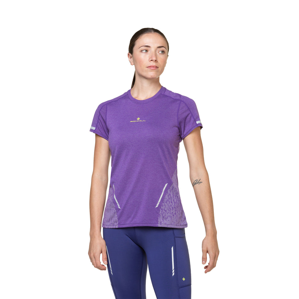Front view of a model wearing a Ronhill Women's Tech Reflect S/S Tee in the Regal Purple/Reflect colourway. Model is also wearing tights. (8489750397090)