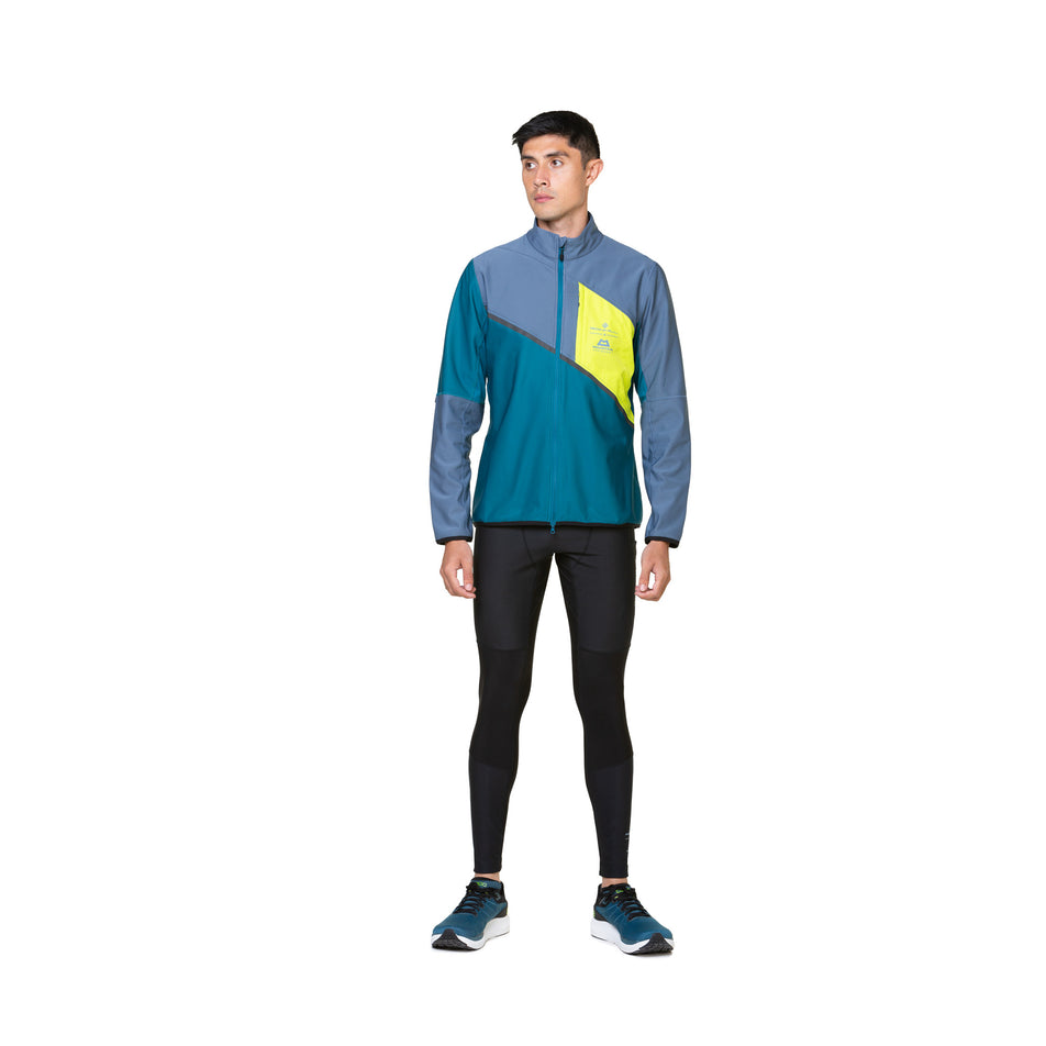Front view of a model wearing a Ronhill Men's Tech GORE-TEX Windstopper Jacket in the Deep Teal/Lake Acid colourway. Model is also wearing tights, socks and shoes. (8470614016162)