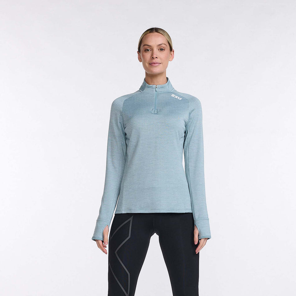 Front view of a model wearing a 2XU Women's Ignition 1/4 Zip top in the Chambray/White Reflective colourway. Model is also wearing leggings. (8108368953506)